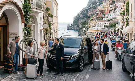 Luxury coach bus dropping off guests in front of a premium hotel overlooking the Amalfi Coast sea