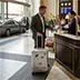 A male tourist leaving a luxury hotel and entering a premium private transfer vehicle for an airport drop-off service